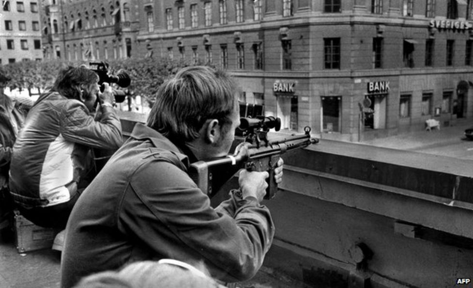 در 24 آگوست 1973، عکاسان مطبوعاتی و تک‌تیراندازان پلیس بامی روبروی بانک در انتظار بودند.